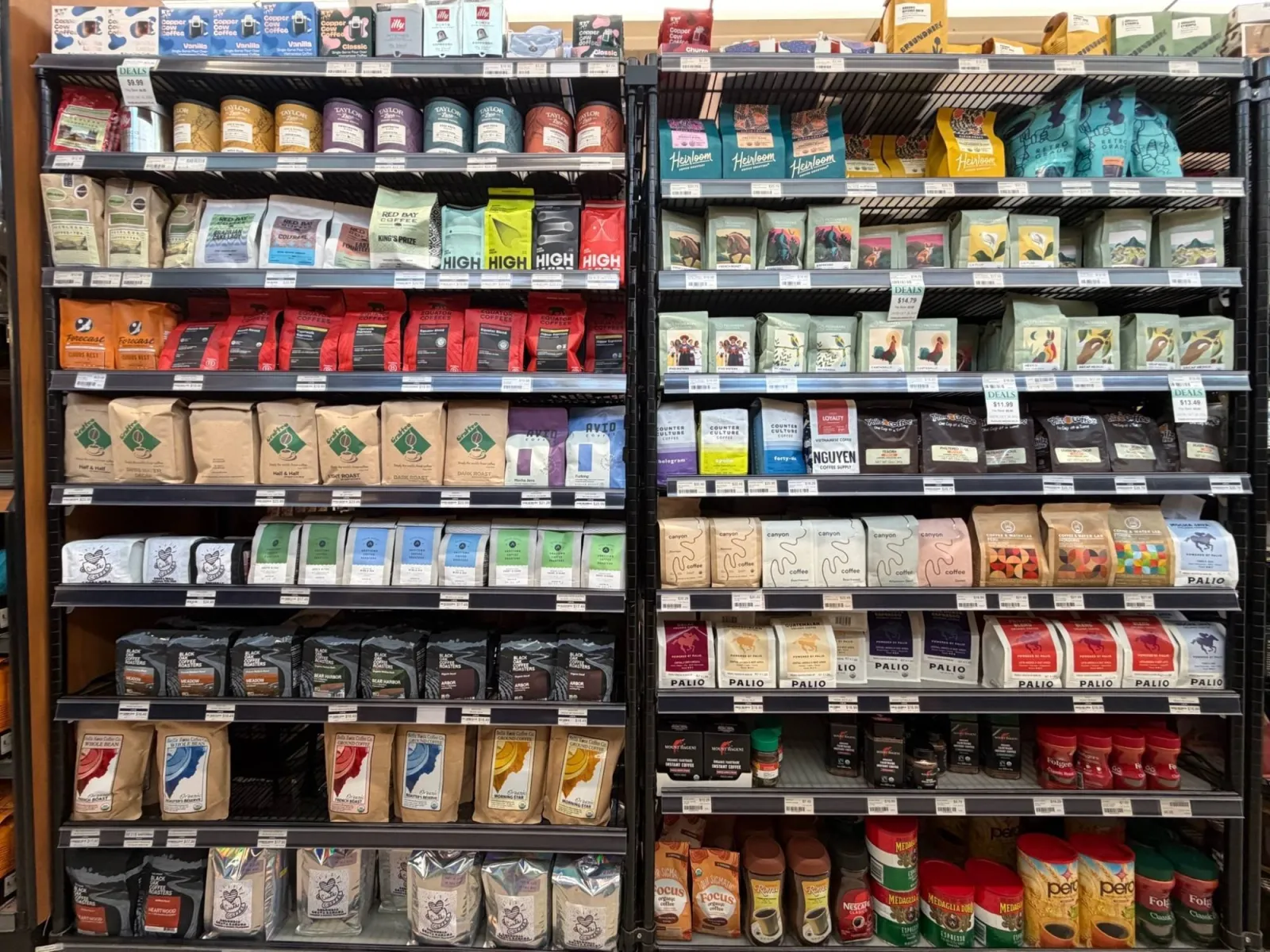 A store shelf stacked with coffee bags from dozens of roasters, from small specialty brands to supermarket tins
